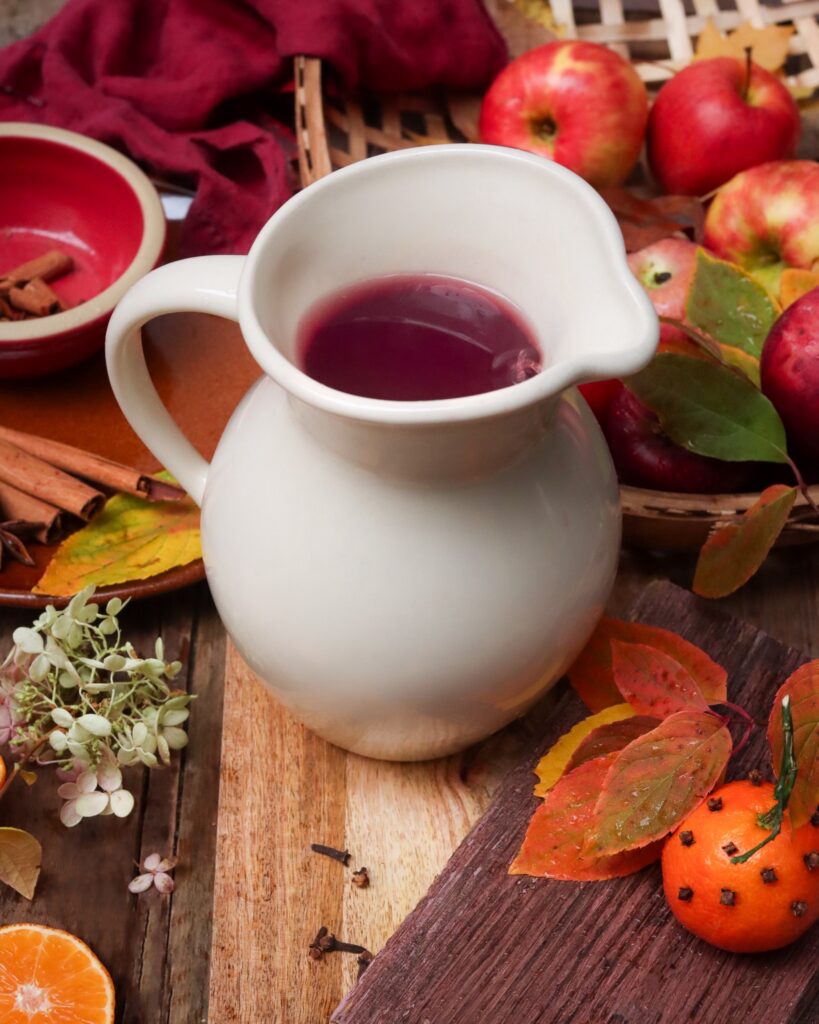Cinnamon cider in stoneware pitcher with apples.